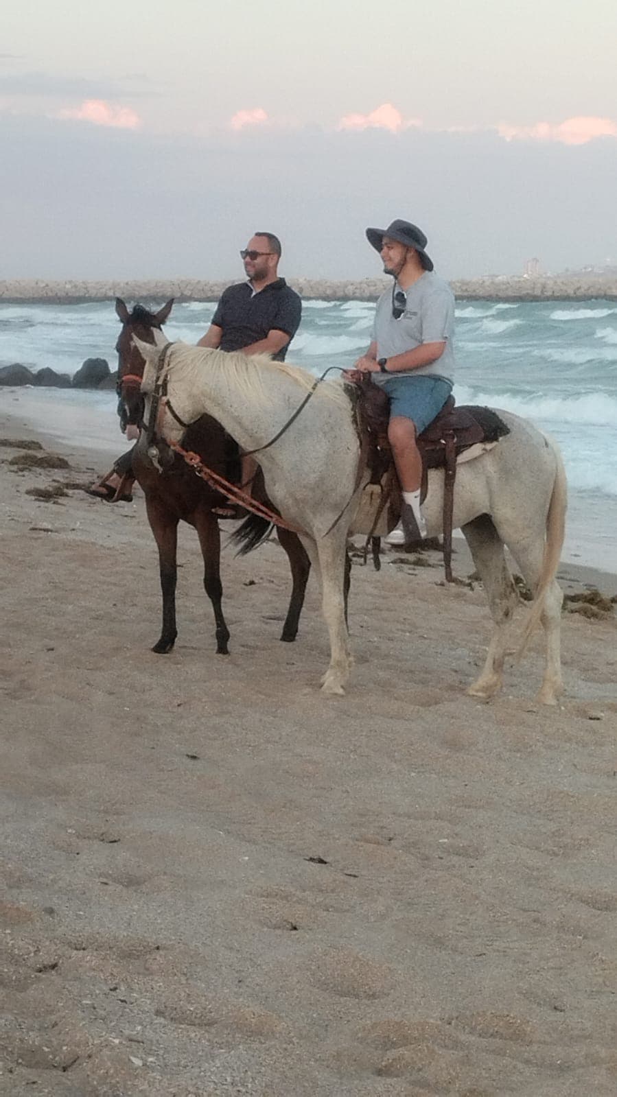 Friends on horseback at the rocky beach
